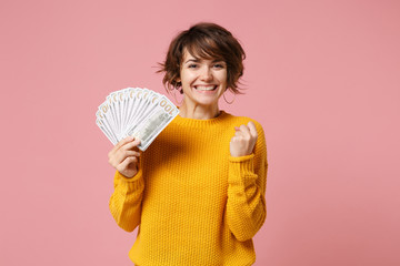 Joyful young brunette woman in yellow sweater posing isolated on pastel pink background. People...