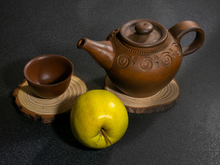 Clay teapot and clay cup and apple