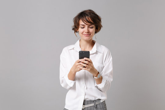 Smiling Young Business Woman In White Shirt Posing Isolated On Grey Background Studio Portrait. Achievement Career Wealth Business Concept. Mock Up Copy Space. Using Mobile Phone, Typing Sms Message.