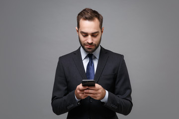 Handsome young business man in classic black suit shirt tie posing isolated on grey background....