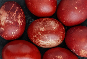 Easter eggs painted in monochrome style close up isolated on black , in red brick color with stains, scuffs, scratches. handmade painted eggs. Flat lay