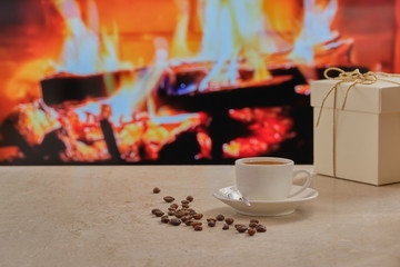 Cup of coffee on a marble table against the background of the fireplace. Coffee beans on the table. Gift box