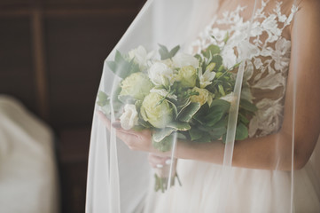 Delicate fresh bouquet in the hands of the bride under the veil 2405.