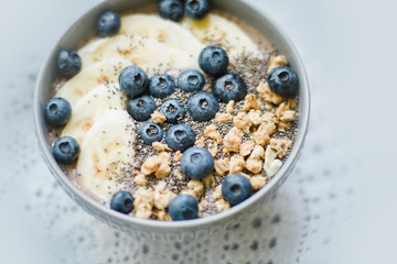 Healthy breakfast berry smoothie bowl topped with banana, granola, Blueberries and chia seeds with copy space