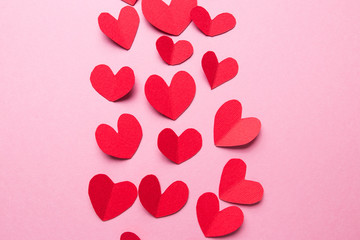 A lot of small hearts of red color against on a pink background. Happy Valentine's Day.