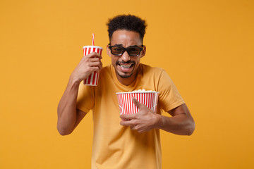 Scared young african american guy in 3d imax glasses posing isolated on yellow orange background....