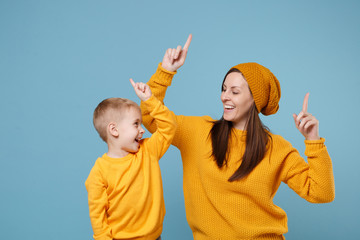Woman in yellow clothes have fun posing with cute child baby boy 4-5 years old. Mommy little kid son isolated on blue background studio portrait. Mother's Day love family parenthood childhood concept.