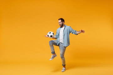 Cheerful young man in casual blue shirt posing isolated on yellow orange wall background, studio...