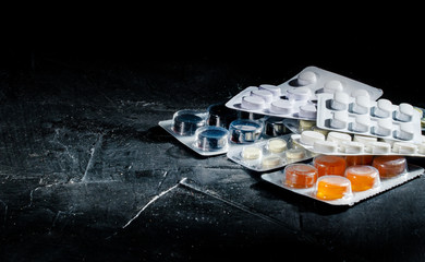 Colorful of tablets and capsules pill in blister packaging arranged on dark background