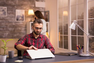 Bearded entrepreneur opening laptop to start working from home