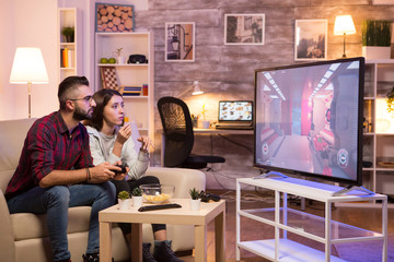 Man sitting on couch and playing video games on television