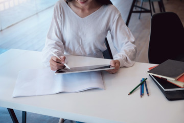 A female designer uses a graphic tablet while working at a studio. To design the work according to the customer.