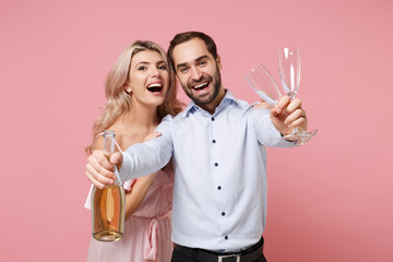 Joyful young couple two guy girl in party outfit celebrating posing isolated on pastel pink...