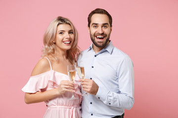 Excited young couple two guy girl in party outfit celebrating posing isolated on pastel pink background. People lifestyle Valentine's Day Women's Day birthday holiday concept. Hold glass of champagne.
