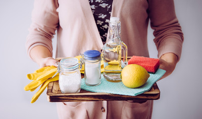 Natural cleaners concept. Woman holding eco friendly home cleaning ingredients, white vinegar,...