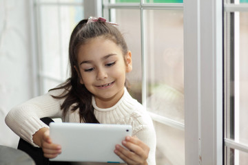 Adorable little child girl using a tablet. Electronic communication