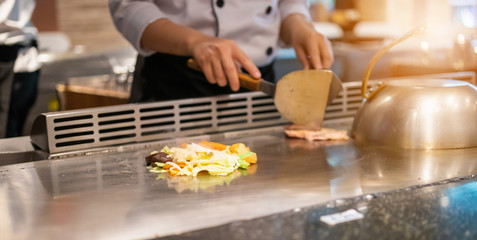 Obraz na płótnie Canvas Japanese chef cooking meat in teppanyaki restaurant