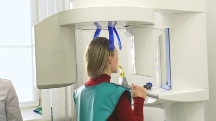 Doctor to take a image 3d scanner tomography of teeth and jaw in modern laboratory dental clinic. Female nurse shows the patient woman an x-ray machine 3d digital scanner. Computer dental diagnostics.
