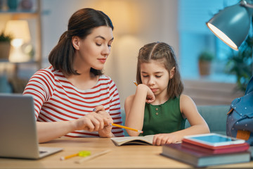 Obraz premium Girl doing homework with mother