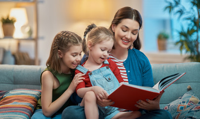 mother reading a book to daughters