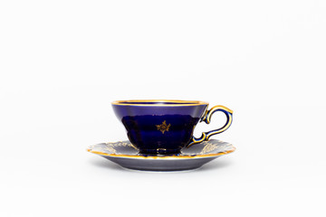 Closeup of a beautiful cobalt blue colored vintage porcelain tea cup with golden floral pattern on white background