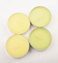 Several small multicolored candles in aluminum casings on a white background. Close up.