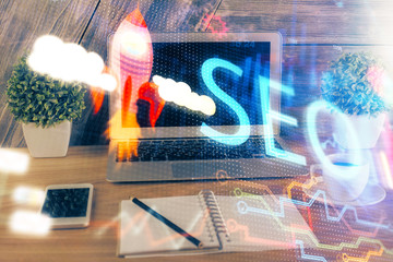 Multi exposure of table with computer and seo drawing hologram. Search optimization concept.