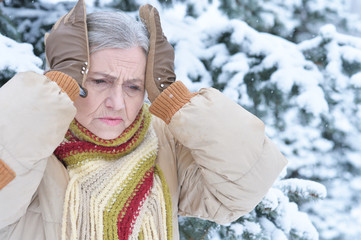Beautiful senior woman with headache in snowy winter park