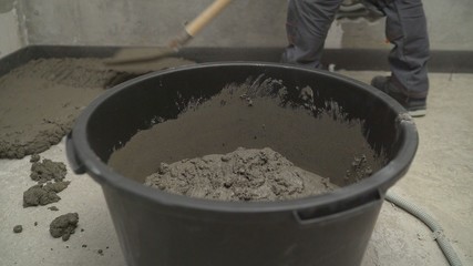 Black bucket with mortar for filling the floor. Bucket with mortar at the construction site.