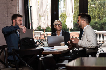 Senior businesswoman holding a meeting with her younger colleagues at office cafeteria.