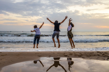 Three kids jumping on a beach at sunset