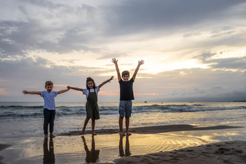 Fototapeta premium Three kids on a beach at sunset