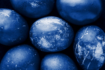 Easter eggs painted in monochrome style close up, tinted in classic blue color trend with stains, scuffs, scratches. handmade painted eggs. Flat lay