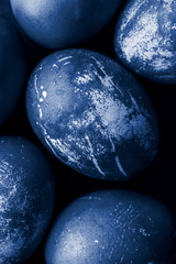 Easter eggs painted in monochrome style close up, tinted in classic blue color trend with stains, scuffs, scratches. handmade painted eggs. Flat lay