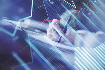 Financial forex graph displayed on hands taking notes background. Concept of research. Multi exposure