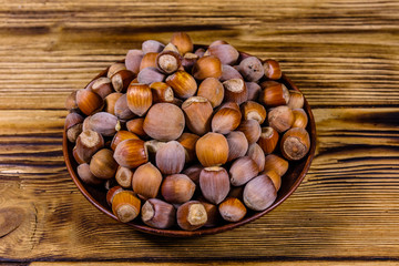 Plate with pile of hazelnuts on a wooden table