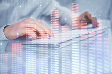 Double exposure of graph with man typing on computer in office on background. Concept of hard work....