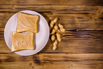 Sandwiches with peanut butter in plate on a wooden table. Top view