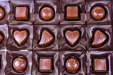 Heap of chocolate candies in a brown box. Top view