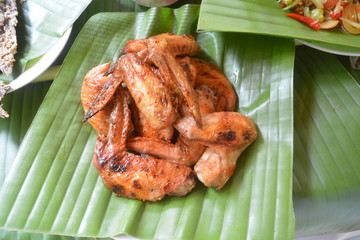 Grilled chicken wings arranged on banana leaves