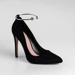 Womens black suede high-heeled shoes with a decorative element ankle bracelet. Close-up. On a white background for a catalog