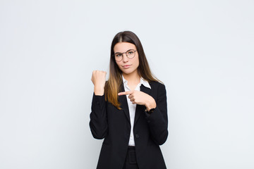 young businesswoman looking impatient and angry, pointing at watch, asking for punctuality, wants...