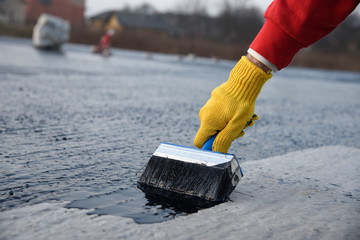Worker applies bitumen mastic on the foundation