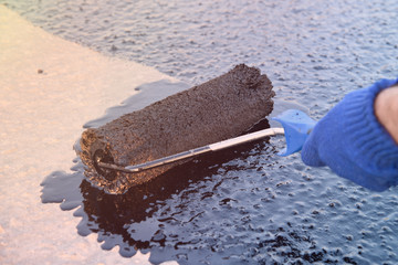 Worker applies bitumen mastic on the foundation