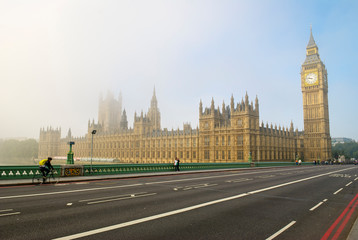 Misty morning view of Big Ben and the Houses of Parliament with unrecognizable people passing in London, UK