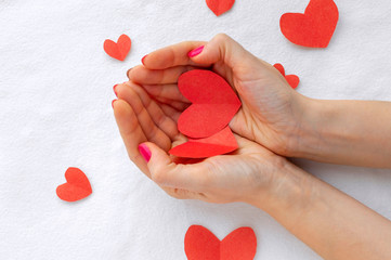 Two red paper hearts in the palms of a girl. The concept of love, love relationships, engagement