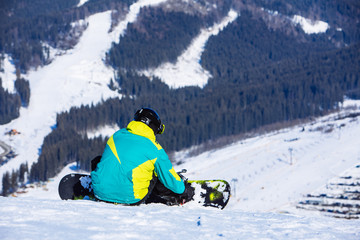 Fototapeta na wymiar man sitting with snowboard on the top of the hill with beautiful view