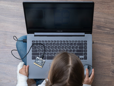 Minsk, Belarus. January, 2020. The BBC robot Micro Bit is connected to a computer. A cute little girl is programming it on Scratch and Python. Creative. Connected. Coding. Learning, teaching easy.