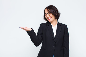 young businesswoman feeling happy and smiling casually, looking to an object or concept held on the...