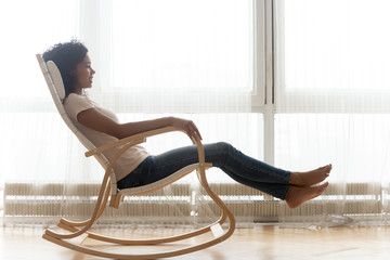 Relaxed african woman resting on wooden rocking chair